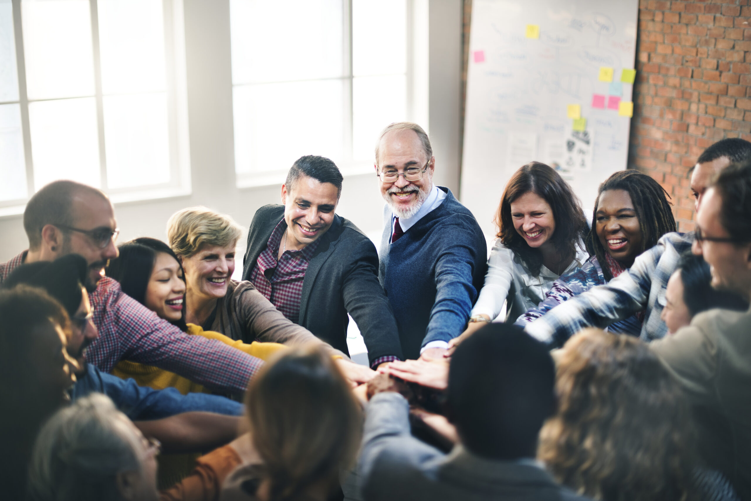 A multiracial team of professionals joining hands enthusiastically, demonstrating excellent company culture.